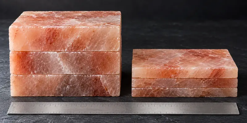 Thick Himalayan salt bricks next to thin Himalayan pink salt tiles with a ruler for scale
